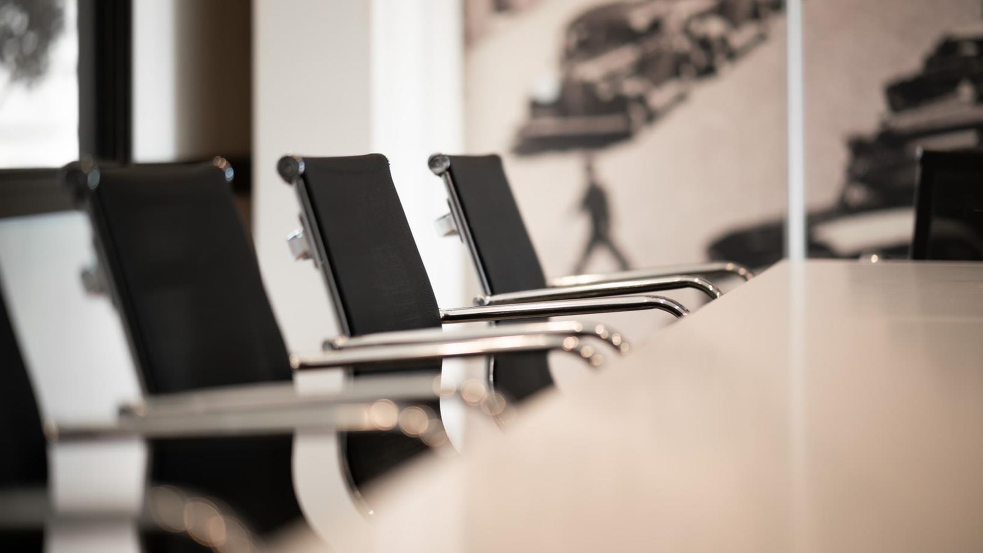 Drei schwarze Bürostühle mit verchromten Armlehnen stehen in einer modernen Umgebung.